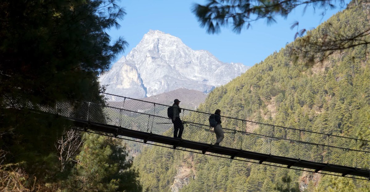 Trekkers crossing a high suspension bridge over a deep gorge on the Everest Base Camp trekking route